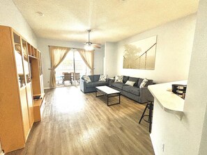 A living room with a sofa, coffee table, and a dining area with chairs. - Family Oasis•15 min to Disney (Kissimmee)