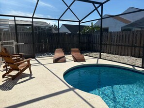 Ein Garten mit Swimmingpool, Holzliegen und einer überdachten Terrasse.