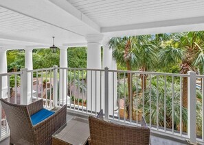 A covered outdoor area with wicker furniture and a view of a landscaped garden. - 1BR/2BA In Baytowne Wharf's Grand Sandestin (Miramar Beach)