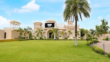 A hotel with a large lawn, palm trees, and a sign reading 'PALETTE Pro-Service'.