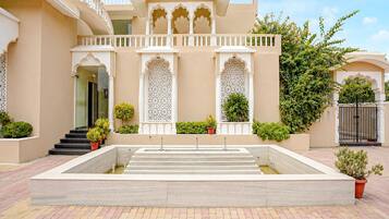 A building with a central courtyard, a staircase leading to the entrance, and a gated entrance.