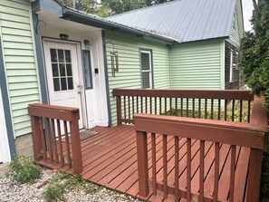 Ein grünes Haus mit einer Holzterrasse und einer weißen Tür.