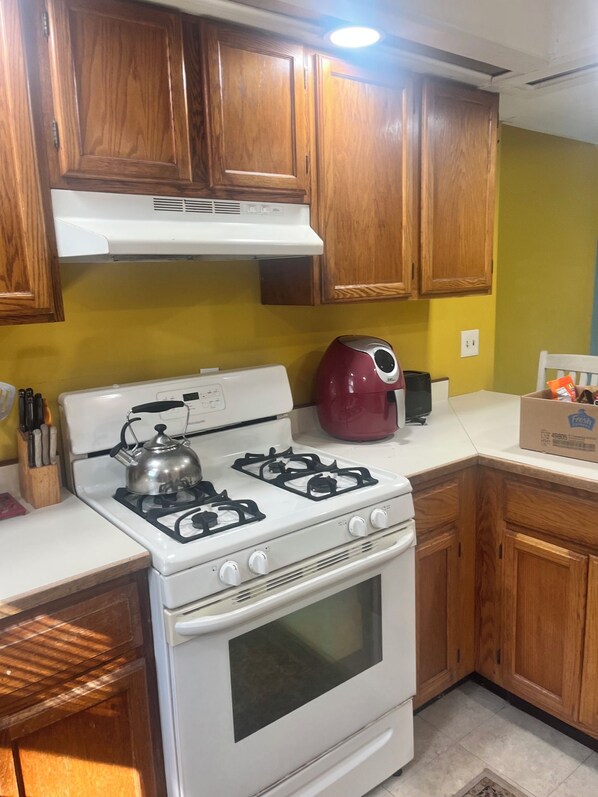 A kitchen with wooden cabinets, a white stove, a red kettle, and a toaster on the counter.