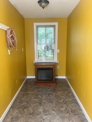 A room with yellow walls, a window, a fireplace, and a tiled floor.