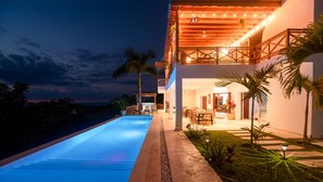 Ein modernes Haus mit Swimmingpool, Essbereich im Freien und einer überdachten Terrasse.