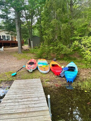 A wooden dock leading to a calm water body with kayaks lined up on the shore. - Cozy 2-bedroom house in tranquil Frederic with AC (Frederic)