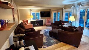 Ein Wohnzimmer mit einer Sofagarnitur, einem Couchtisch, einem Fernseher und einem Kamin.