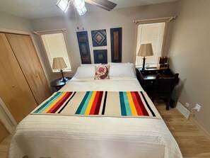 A bedroom with a bed, two nightstands, a desk, a wardrobe, and a ceiling fan. - Cozy 2-bedroom house in tranquil Frederic with AC (Frederic)