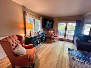 A living room with a fireplace, a television mounted on the wall, and a large window. - Cozy 2-bedroom house in tranquil Frederic with AC (Frederic)