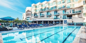 Een hotel met een zwembad, ligbedden en een wellnessruimte.