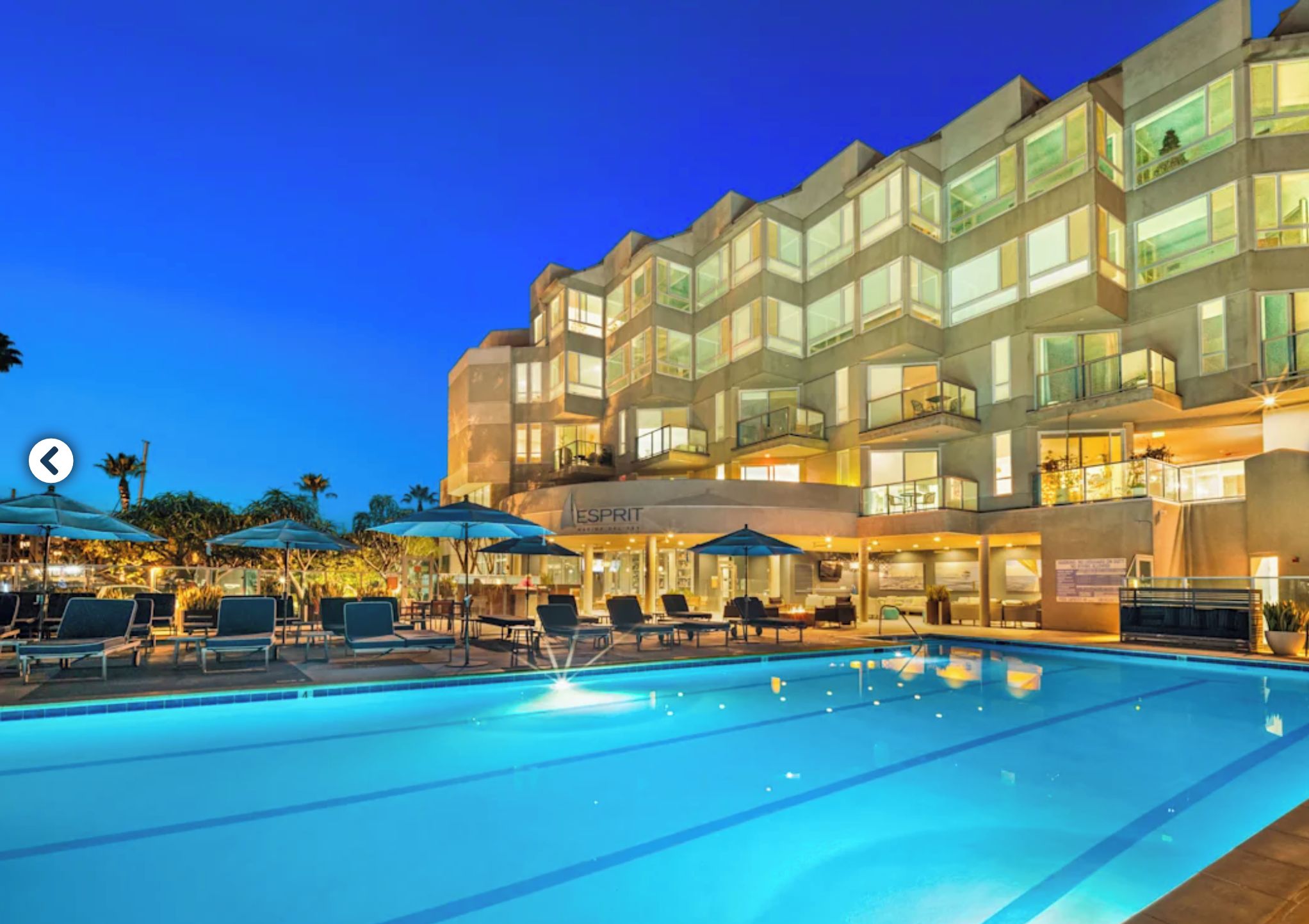 A hotel with a swimming pool, outdoor seating, and a bar area.