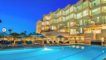 A hotel with a swimming pool, outdoor seating, and a bar area.