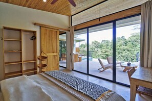 Ein Schlafzimmer mit einem großen Bett, einem Holzschrank und Blick auf einen Pool sowie eine Sitzgelegenheit im Freien.