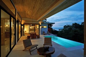 Ein moderner Außenbereich mit Pool, Sitzgelegenheiten und Meerblick.