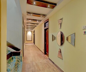 Un pasillo con piso de madera, una escalera con barandillas de metal y una puerta con espejo.