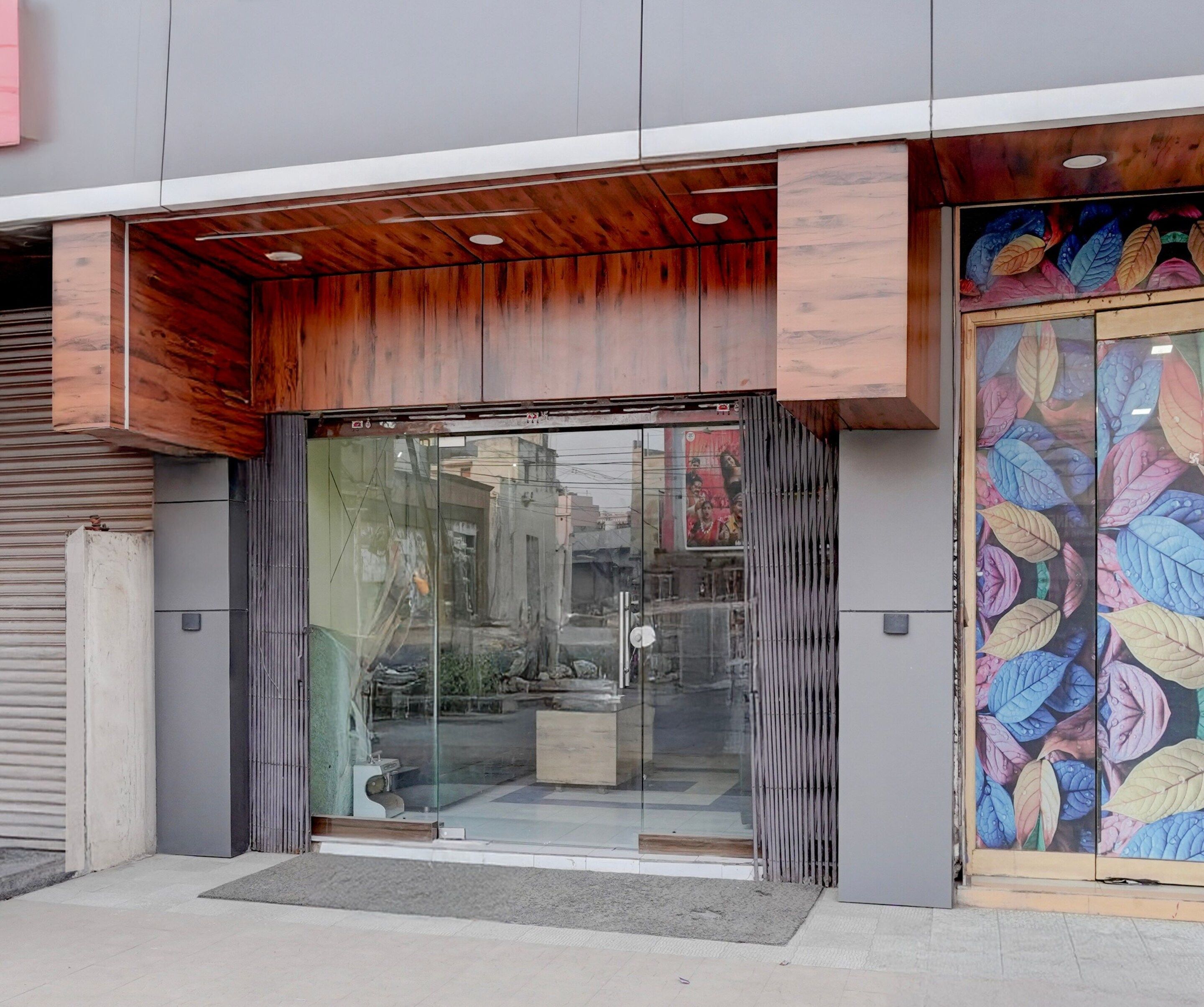A building entrance with a wooden overhang, glass doors, and a colorful leaf-patterned door.