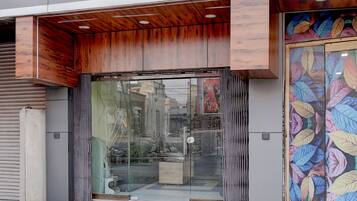 A building entrance with a wooden overhang, glass doors, and a colorful leaf-patterned door.