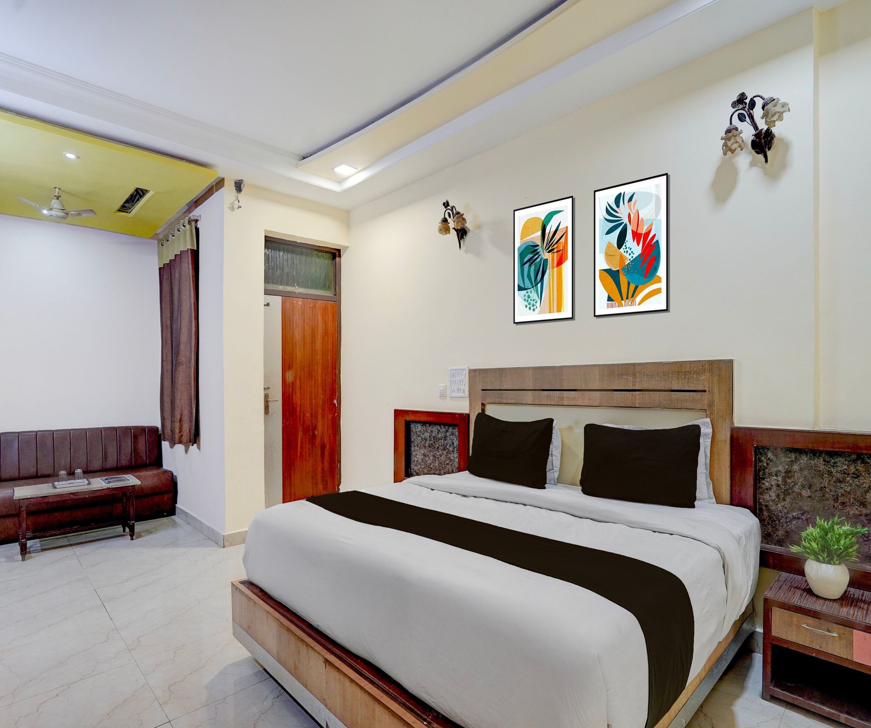 Un dormitorio con cama, cabecera de madera, mesita de noche, banco y lámpara de pared.