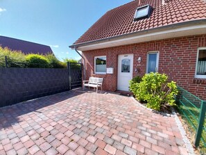 A brick house with a tiled roof, a front door, and a bench outside. - Eric's Holiday Home (Krummhoern)