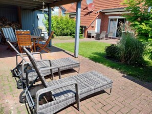 An outdoor seating area with wicker furniture and a covered patio. - Eric's Holiday Home (Krummhoern)