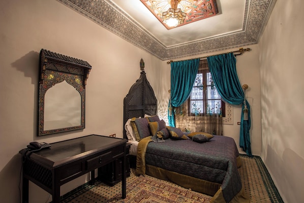 A bedroom with a bed, a desk, a telephone, and a decorative ceiling. - Ryad Naila  (Fès)