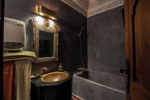 Een badkamer met een oud badkamermeubel, een spiegel en een bad.
