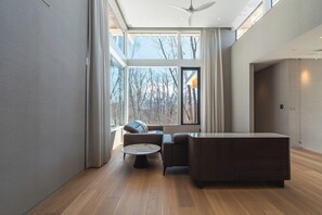 A modern living room with a large window, a sofa, a coffee table, and a wooden cabinet.