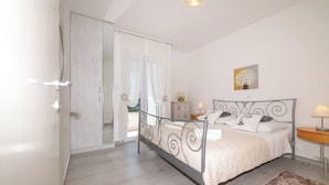 A bedroom with a bed, a bedside table, a lamp, a painting, and a view through a door. - 4-Bedroom Villa in Vis w/ Private Pool & Parking (Vis)