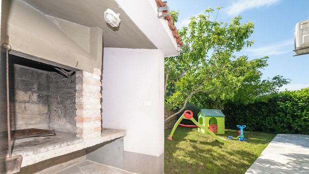 A patio area with a fireplace, a play structure, and a green playhouse. - 4-Bedroom Villa in Vis w/ Private Pool & Parking (Vis)