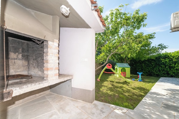 Un espace extérieur aménagé avec un foyer, une structure de jeu et une petite maison de jeu verte.