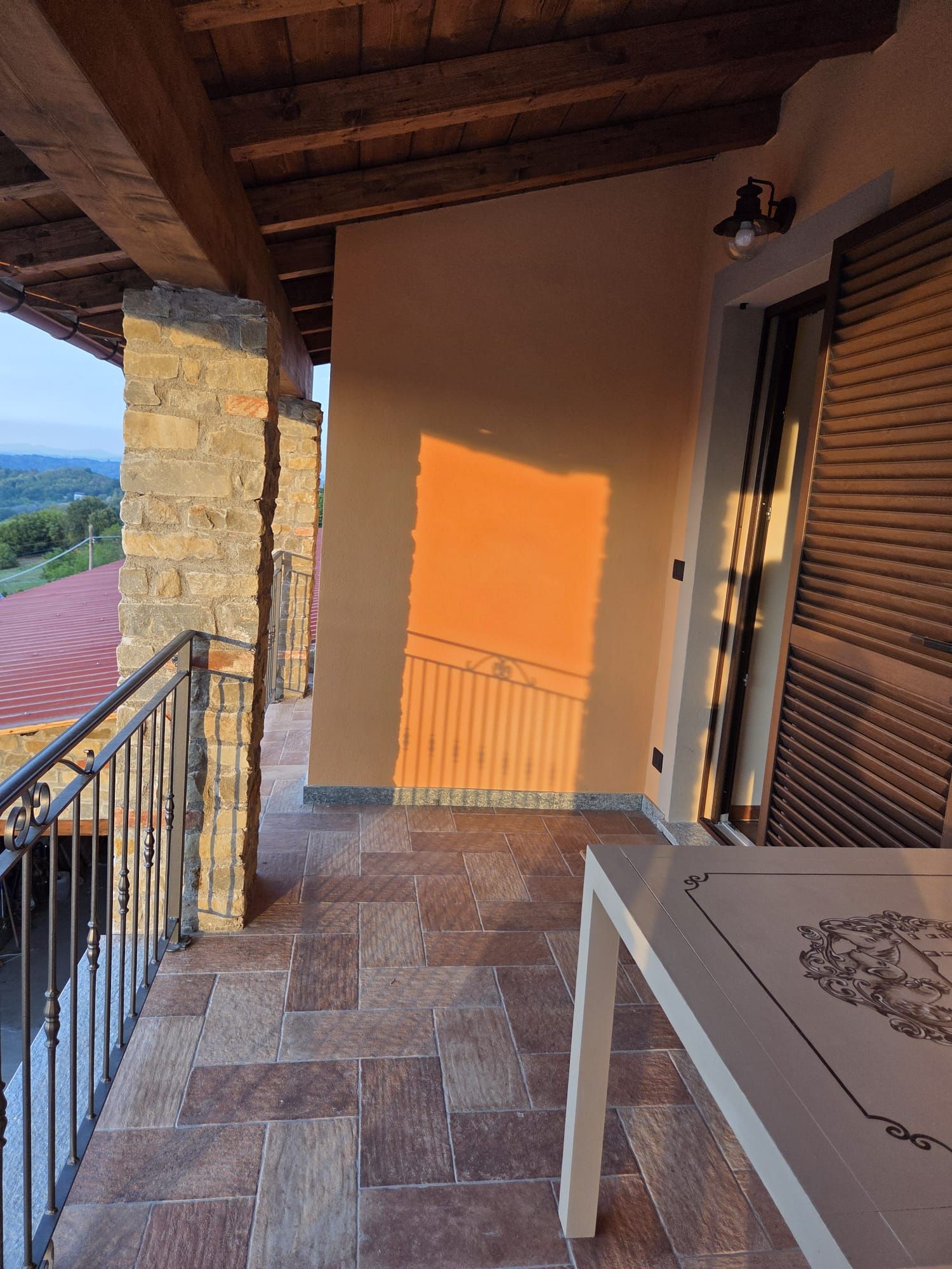 Un balcone con pareti in pietra, pavimento piastrellato e vista sul paesaggio.