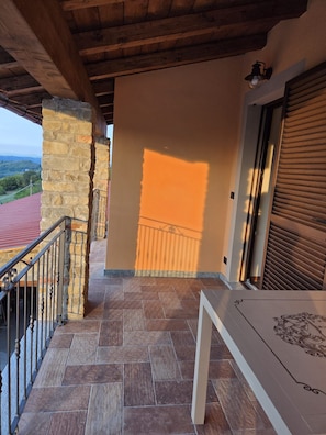 Un balcó amb parets de pedra, un paviment de rajoles i vista al paisatge.