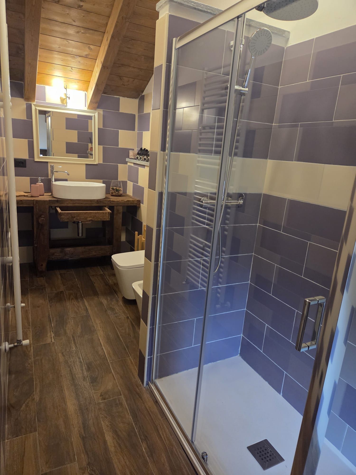 Une salle de bain moderne avec une douche à parois de verre, un meuble-lavabo en bois et des toilettes blanches.