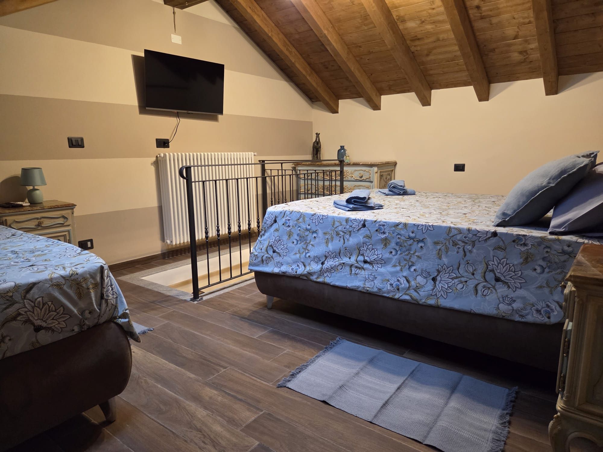 A bedroom with a bed, a desk, a radiator, and a television.