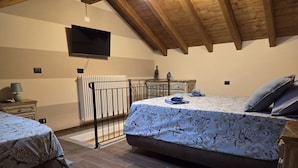 A bedroom with a bed, a desk, a radiator, and a television. - LA NOCCIOLINA CASCINA MOSE, nestled in nature among farm animals (Ovada)