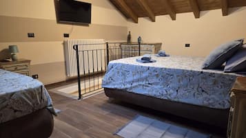 A bedroom with a bed, a desk, a radiator, and a television.