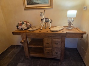 A wooden desk with a decorative horse figurine, a lamp, and a floral arrangement. - LA NOCCIOLINA CASCINA MOSE, nestled in nature among farm animals (Ovada)