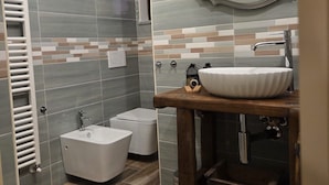 A bathroom with a wooden vanity, a white sink, a bidet, and a mirror. - LA NOCCIOLINA CASCINA MOSE, nestled in nature among farm animals (Ovada)