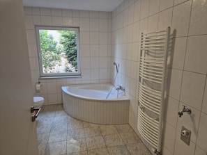 Ein Badezimmer mit einer Badewanne, einem Fenster und einem Handtuchhalter.
