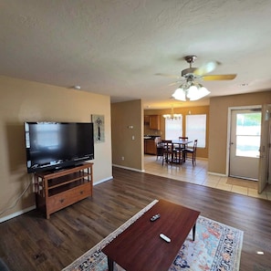 A living room with a flat-screen TV on a wooden stand, a coffee table, and a rug.