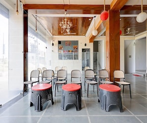 Een kamer met een hoge plafond, houten balken en een reeks stoelen en tafels voor zitplaatsen.