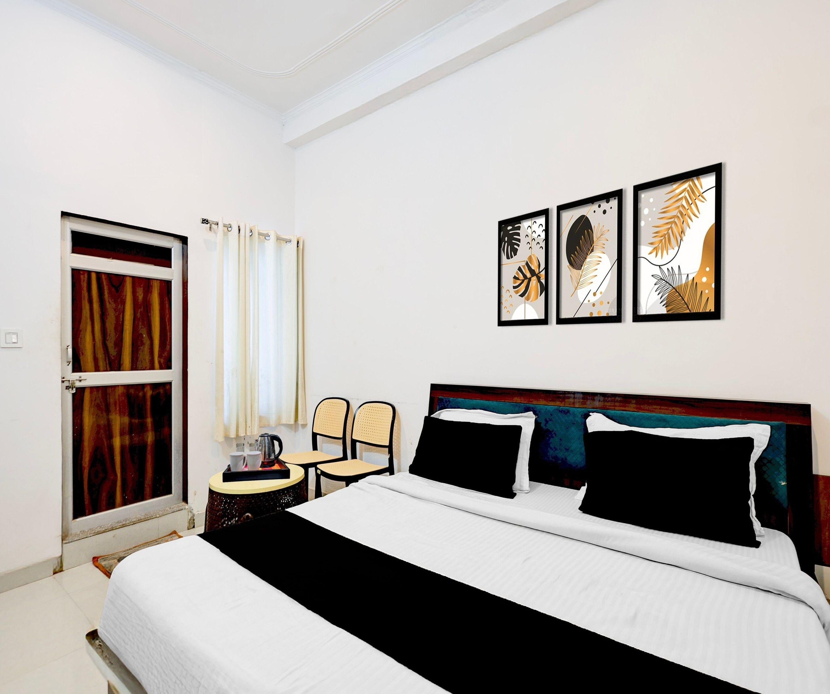 Una camera d'albergo con un letto, un tavolino con un bollitore, due sedie e una porta con tende.