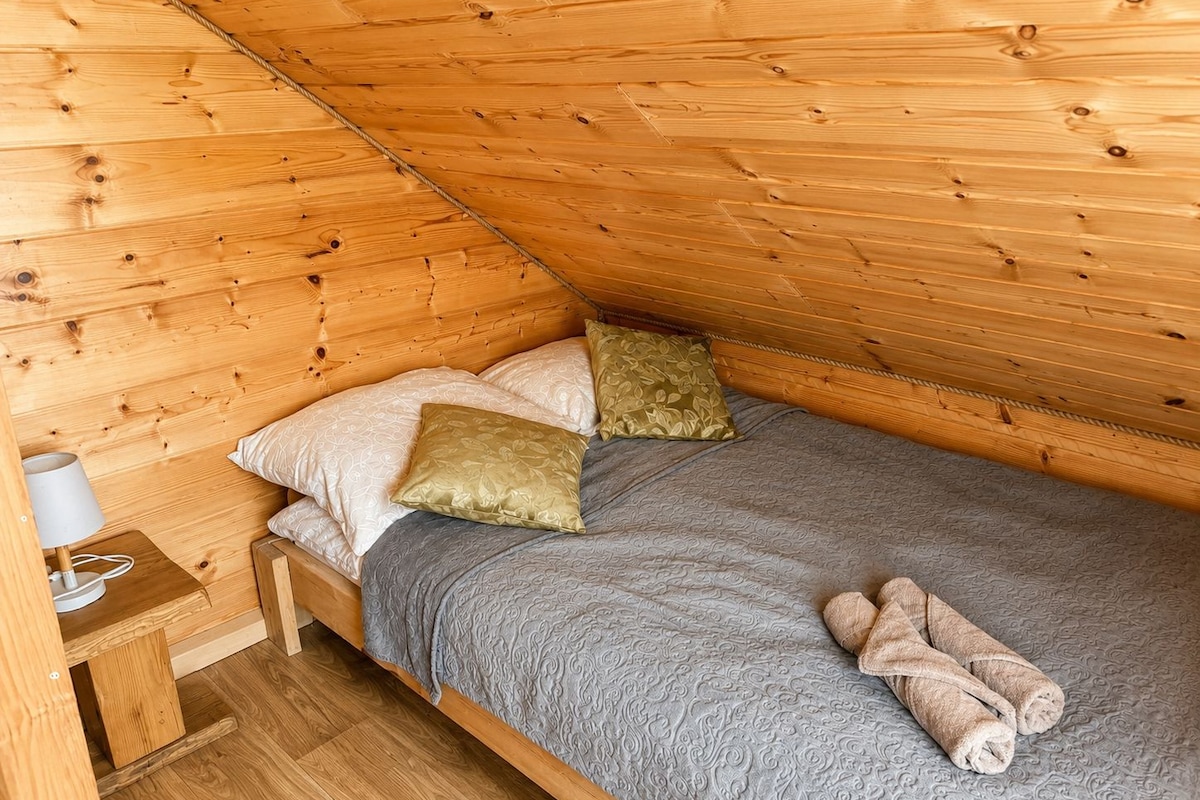A small, cozy room with a single bed, a nightstand, and a lamp.