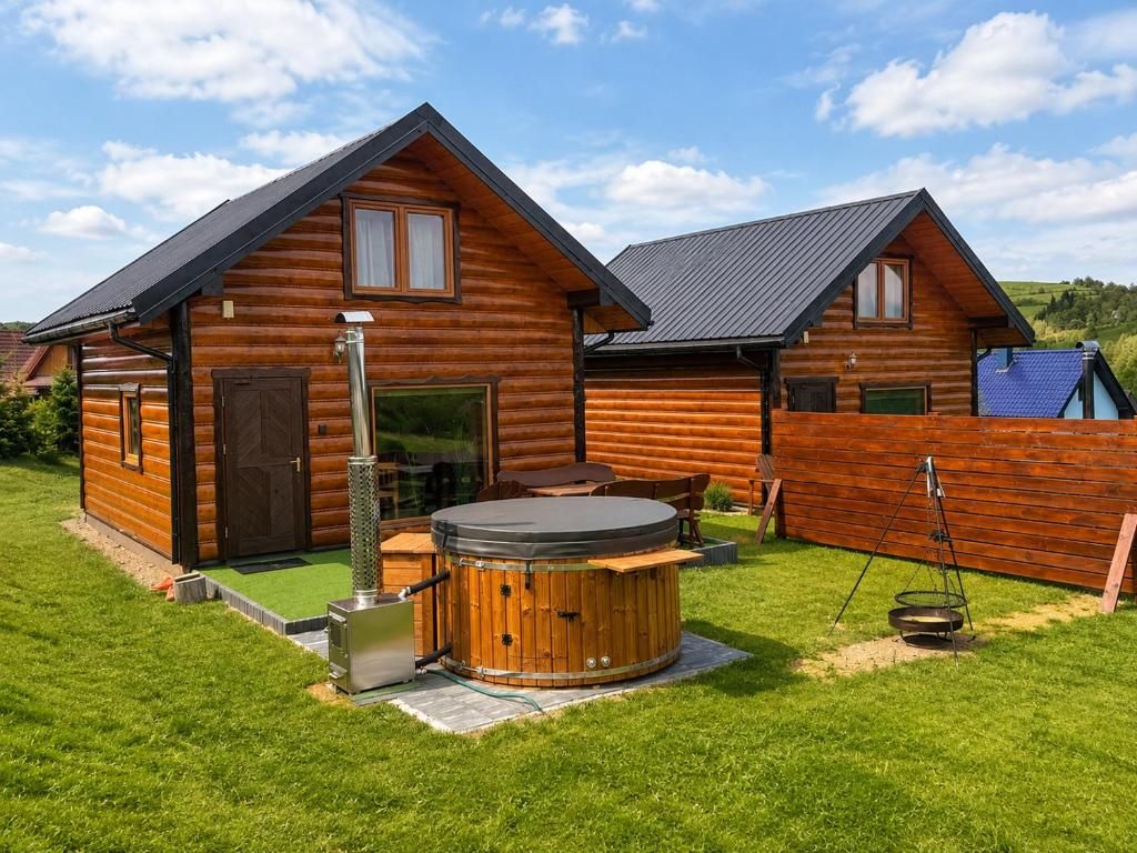 A log cabin with a hot tub and a wooden deck.
