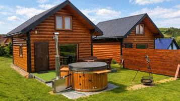 A log cabin with a hot tub and a wooden deck.