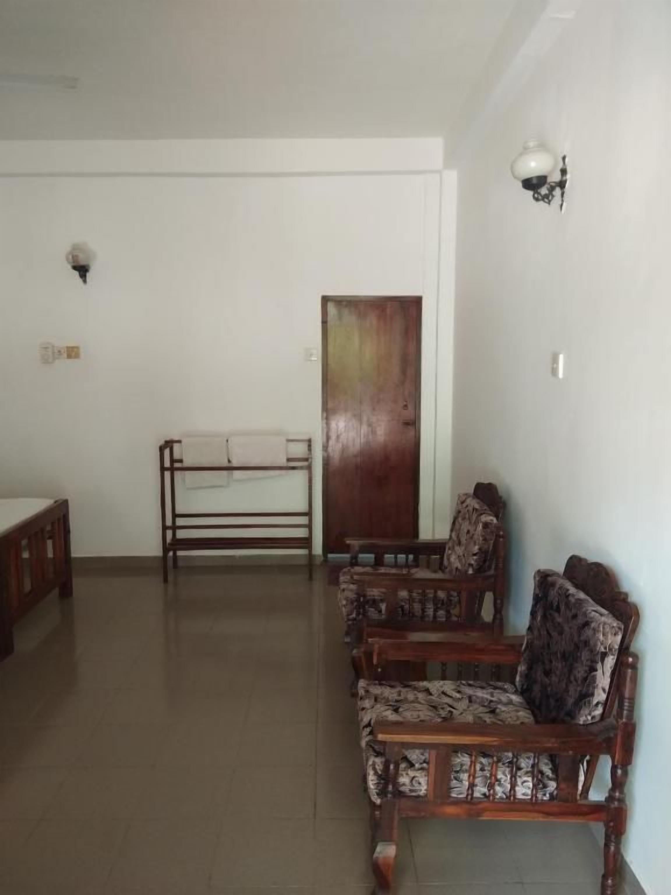 Una habitación con un banco de madera, una mesa y sillas estampadas.