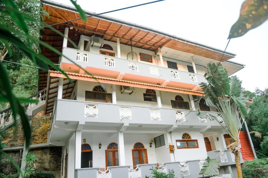A multi-story building with balconies, a stone facade, and a wooden roof.