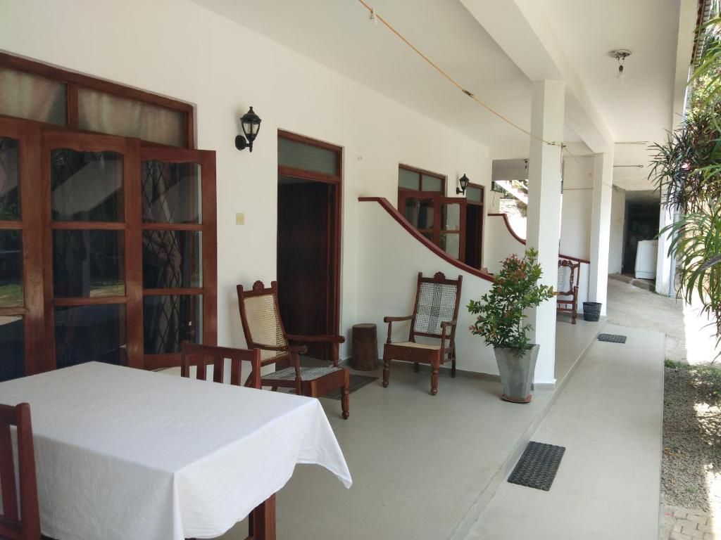 Un espace extérieur abrité, avec une table et des chaises, une plante en pot et un escalier.