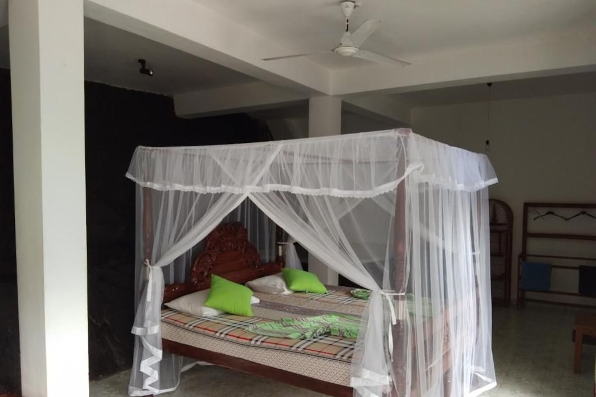 A bed with a canopy, a ceiling fan, and a bed frame with a patterned bedspread.