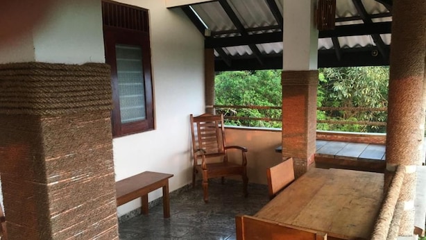 Una habitación con una mesa y sillas de madera, un banco y un ventanal con vista a zonas verdes.